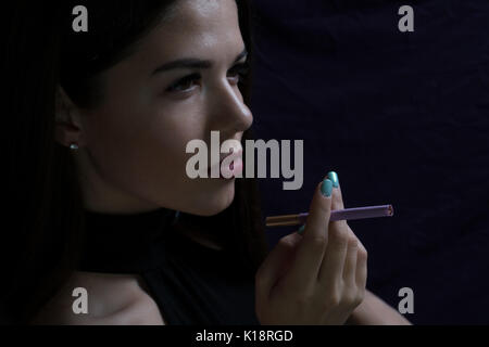 Portrait de la belle fille élégante cigarette isolé sur fond sombre. Banque D'Images