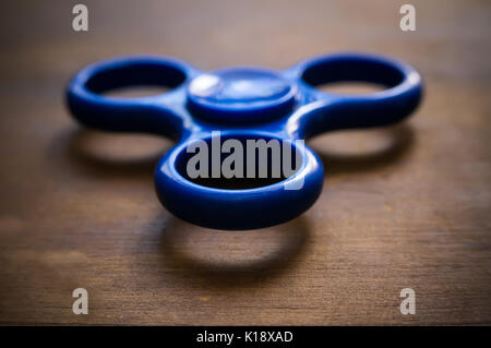 Fidget bleu spinner isolé sur table en bois. Puissant, spinner spinner, Twister pour mains en rotation animation Toy Banque D'Images