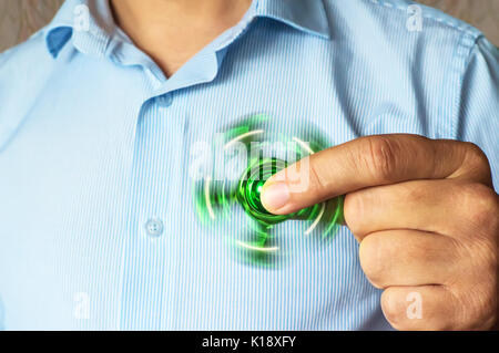 Spinner spinning vert dans la main d'un homme d'affaires dans une veste et une chemise. Spinner puissant, Twister pour mains en rotation animation jouet. Antistre Banque D'Images