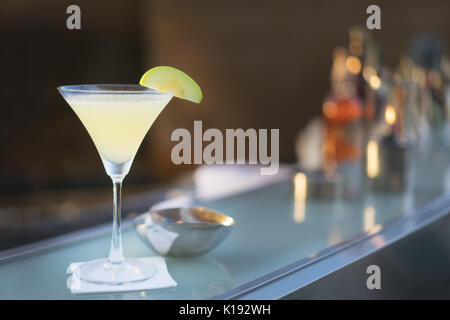Cocktail sans alcool martini apple tourné au bar avec bar comptoir en arrière-plan.
