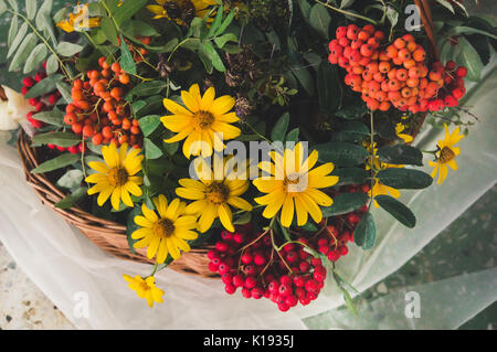 Bouquet d'automne avec des fleurs de jardin et les branches de mountain ash dans panier jaune et tissu blanc teinté photos instagram. Banque D'Images