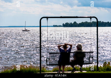 Un homme et une femme bénéficiant d'une journée chaude et ensoleillée d'un swing sur la rive d'un lac, Québec, Canada Banque D'Images