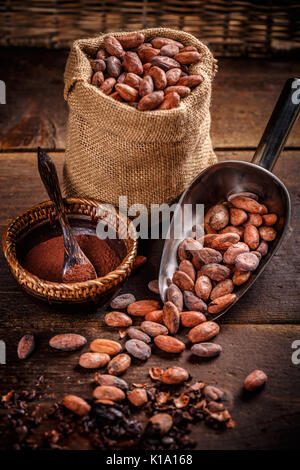 Cacao biologique en poudre dans le bol et fèves de cacao dans scoop et en sac de jute Banque D'Images