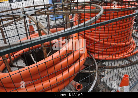 Les tiroirs de tube géant orange pour la pose de câbles à fibre optique sont stockées en toute sécurité à un chantier clôturé dans un emplacement urbain, de l'Ontario, Canada. Pas de travailleurs. Banque D'Images