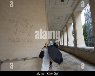 Femme avec parasol passant devant les bureaux Prudential dans le centre de Londres Banque D'Images