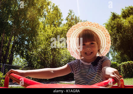 Une petite fille un carrousel équestre sur l'aire de jeu. Animation pour enfants dans la nature dans le parc Banque D'Images