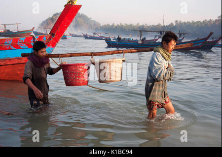 Les pêcheurs birmans mettre à terre paniers de poissons sur la plage de Ngapali Myanmar à l'aube Banque D'Images