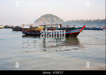 Flotte de pêche des bateaux amarrés dans les eaux calmes de la plage de Ngapali Myanmar comme le soleil se lève à l'aube Banque D'Images