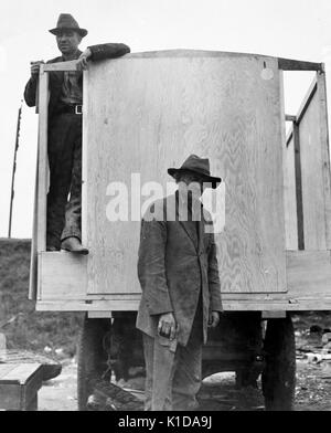 Mature sombre père (vu) et la tenue d'un fils adulte (comité permanent sur la structure), à la fois porter des vestes et chapeaux, la construction d'une maison sur roues de gros morceaux de bois, yuba County, Californie, 1936. à partir de la bibliothèque publique de new york. Banque D'Images