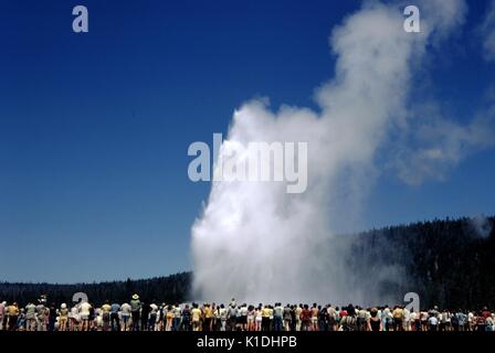 Une foule importante, s'étendant d'un côté de la photo à l'autre, les montres de l'éruption du geyser Old Faithful, le Parc National de Yellowstone, Wyoming, 1982. Banque D'Images