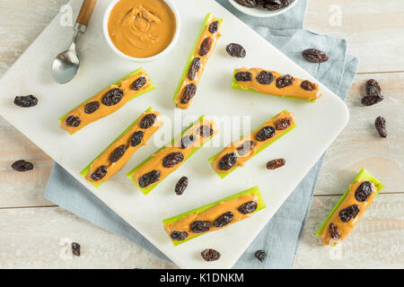 Des fourmis sur un journal Snack avec du beurre d'arachides et raisins Céleri Banque D'Images