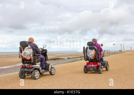 Deux utilisateurs de fauteuils roulants motorisés à Thorton, Cleveleys, Royaume-Uni. Août 2017. UK Météo. Senior, pensionné personne handicapée utilisant un scooter de mobilité sur un début couvert de la journée sur la côte de Fylde près de Blackpool avec peu de signe d'une fin chaude à la saison des vacances d'août. Banque D'Images