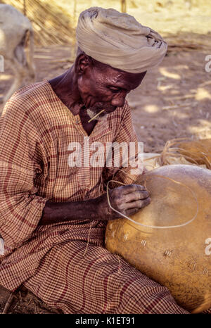 Delaquara, Niger, Afrique de l'Ouest. Homme sourd réparant un calebasse. Banque D'Images
