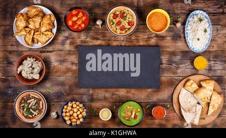 La nourriture indienne assorties sur un fond de bois. Plats et apéritifs de la cuisine indienne. Curry de poulet, beurre, riz, lentilles, Panir aux épinards, samosa, naan Banque D'Images