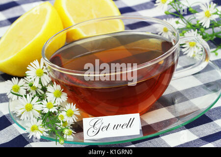 Carte de prompt avec une tasse de thé, de fleurs de camomille et de citron frais Banque D'Images