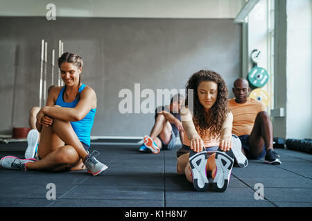 Mettre en place deux jeunes femmes dans les vêtements de sport et d'étirements sourire ensemble avant d'assister à un cours dans un club de santé Banque D'Images