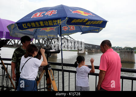 Dandong, province de Liaoning, Chine - 29 juillet 2017 : les touristes à la recherche au moyen d'un télescope à partir de la rivière Yalu pont cassé à Sinuiju en Corée du Nord. Banque D'Images