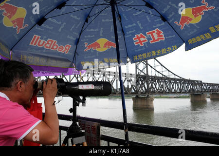 Dandong, province de Liaoning, Chine - 29 juillet 2017 : les touristes à la recherche au moyen d'un télescope à partir de la rivière Yalu pont cassé à Sinuiju en Corée du Nord. Banque D'Images