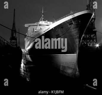 Photographie de nuit QE2 dans le King George V dock sec. à quais de Southampton, Southampton, Hampshire, Angleterre, où elle a d'atterrissage pour hélicoptères équipés pour le service dans la guerre des Malouines - Mai 1982 Banque D'Images