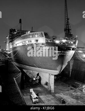 Photographie de nuit QE2 dans le King George V dock sec. à quais de Southampton, Southampton, Hampshire, Angleterre, où elle a d'atterrissage pour hélicoptères équipés pour le service dans la guerre des Malouines - Mai 1982 Banque D'Images