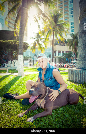 L'homme et le chien bull-terrier américain de mine de détente à l'initiative Faire place au parc et s'étreindre Banque D'Images