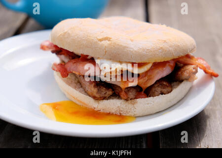 Un petit-déjeuner fraîchement préparé PAB. Bacon, saucisses et œufs frits cuits à un café en plein air et servi dans un petit pain. Banque D'Images