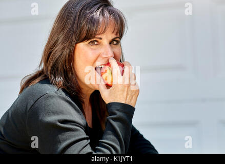 Belle femme d'âge moyen tenant une pomme dans sa main la préparation de mordre il Banque D'Images