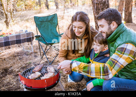 Close-up portrait of happy family griller la viande sur barbecue in autumn park Banque D'Images