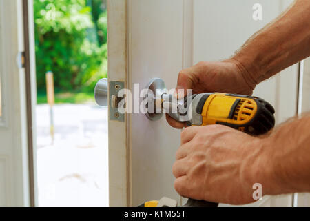 Installation d'un verrou sur la porte d'entrée de la main avec un tournevis pour l'homme installe bouton de porte. Banque D'Images