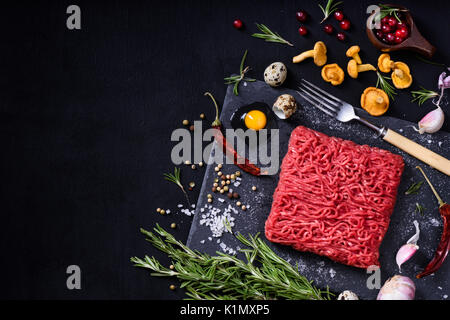 Matières premières ou de veau savoureuse viande de boeuf sur le tableau noir. Ingrédients de cuisson avec la viande hachée. Vue de dessus, copiez l'espace. Banque D'Images