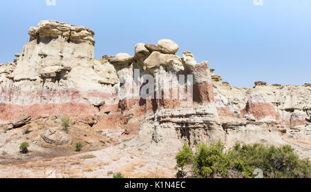 Une partie de la groseille Creek Canyon Badlands mur avec tan, rose, gris et rouille bandes. La végétation clairsemée est au premier plan. Banque D'Images