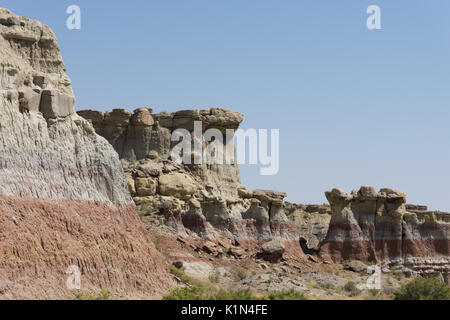 Une partie de la groseille Creek Canyon Badlands mur avec tan, rose, gris et rouille bandes. La végétation clairsemée est au premier plan. Banque D'Images