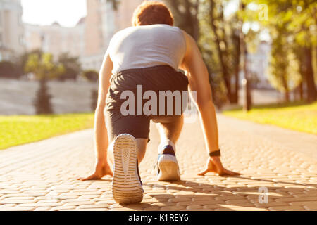 Jeune homme athlétique jogging à matin. De faibles étoiles. Modèle de remise en forme dans le crossfit exercice à l'extérieur. Concept de vie sain. Banque D'Images