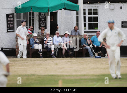 À l'embargo le lundi 28 août 0001 spectateurs assis à l'extérieur de l'Barley Mow pub de regarder un match de cricket village entre Tilford et Grayswood joué sur le green en Tilford, Surrey, le samedi 15 juillet 2017. Banque D'Images