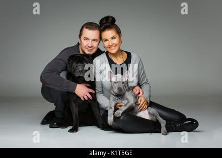 Beau couple d'âge moyen avec thai ridgeback chiot Shar Pei noir et chiens. studio shot sur fond gris. copier l'espace. Banque D'Images