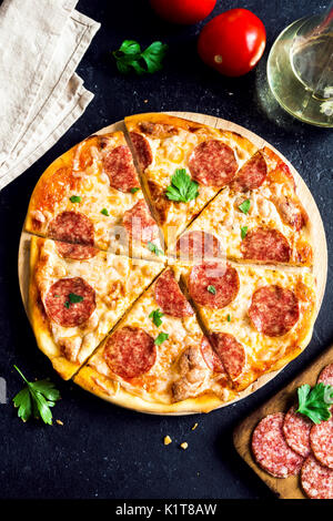 Pizza au pepperoni, avec des ingrédients - Produits frais des pizzas avec pepperoni, fromage et sauce tomate et ingrédients sur pierre noire avec fond rustique Banque D'Images