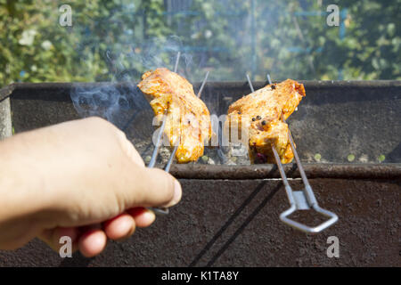 La cuisson des viandes à un pique-nique. La viande de porc étant rôti entier sur une brochette sur feu ouvert. Close-up chachlik macro morceaux de viandes de porc à la broche. Shi Banque D'Images