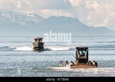 Bateaux de pêche en voiture jusqu'à l'attente d'un remorqueur tracteur qui devront les mettre en retour à la terre sur la plage de point d'ancrage, de l'Alaska. La rampe de mise à l'unique utilise les débusqueuses pour remorquer les bateaux de pêche de la Cook Inlet jusqu'à la plage de l'aire de stationnement et est le résultat de l'extrême qui permettrait de lancer un bateau impossible autrement. Banque D'Images