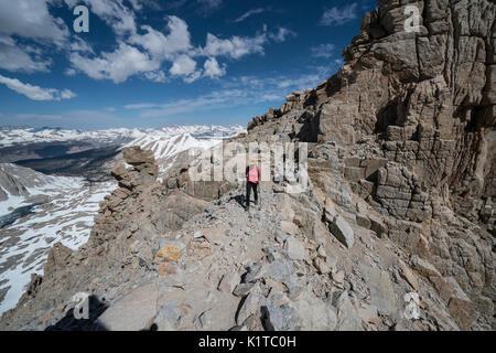 Une femme des randonnées à travers l'un des célèbre Trail Crest windows sur la descente du sommet du Mt. Whitney. Banque D'Images