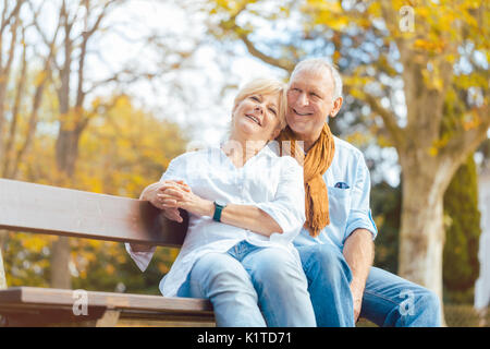 Senior couple sitting on bench in autumn park Banque D'Images