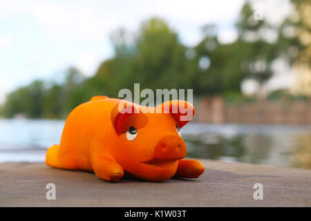 Peu de couleur orange lumineuse cochon jouet en latex est à la banque de la Spree à Berlin Charlottenburg Banque D'Images