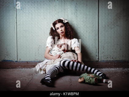 Portrait d'une étrange jeune fille solitaire avec des poupées en lieu abandonné Banque D'Images