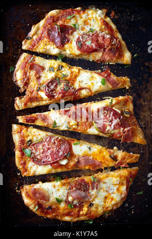 Une forme ovale rustique des pizzas avec du fromage, des tranches de tomates heirloom, prosciutto et basilic frais déchiré. Banque D'Images
