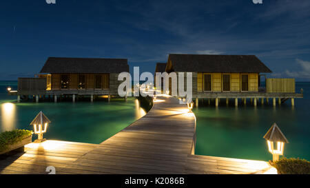 Cabanes de bois sur pilotis dans la lagune à Gangehi Island, nuit, Ari Atoll, Maldives, océan Indien Banque D'Images