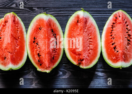 Arrière-plan de tranches de melon frais mûrs sur table en bois noir. Vue d'en haut. Banque D'Images