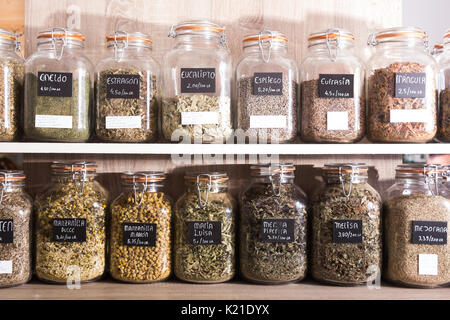 De nombreuses boîtes de verre avec différentes herbes séchées debout sur étagère dans food store Banque D'Images