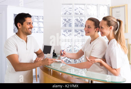 Smiling young guy parlant avec cheerful young nurses in medical clinic Banque D'Images