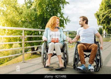 Couple émotionnel reposant à l'extérieur, dans le fauteuil roulant Banque D'Images