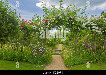 Vaste et superbe jardin anglais avec étang circulaire, Frontières herbacées, et par voie de rosiers grimpants à archway jardins Rousham Banque D'Images