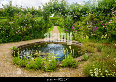 Vaste et superbe jardin anglais avec étang circulaire, Frontières herbacées, et par voie de rosiers grimpants à archway jardins Rousham Banque D'Images